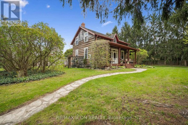 Wide exterior shot of a historic log home with a meandering stone path through the yard. - 630 Robert Ferrie Drive, Kitchener