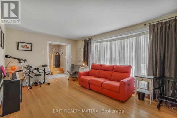 Living and dining area with hardwood floors, green walls, sofa, television, and dining table. - 630 Thorne Street, Hawkesbury