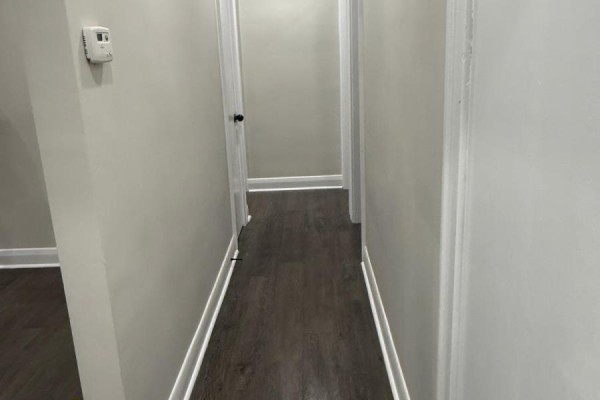Interior hallway with light grey walls, dark wood-look flooring, and multiple doors. - 6300 Corwin Crescent, Niagara Falls