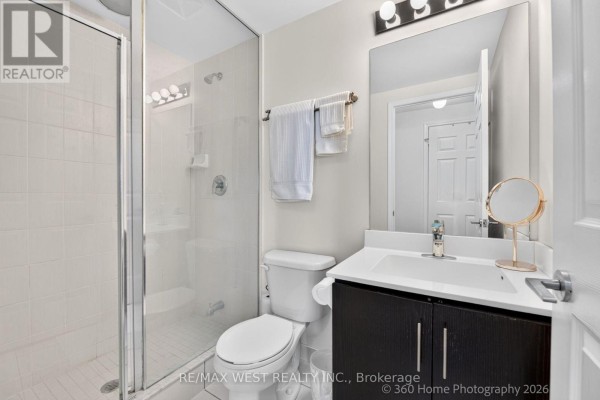 Compact bathroom with a dark wood vanity, white countertop sink, toilet, and glass-enclosed shower. - 631 - 15 James Findlay Way, Toronto