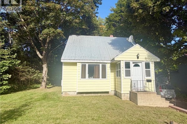Front exterior of a small yellow house with a lawn and mature trees. - 631 Mitchell Street, Fredericton