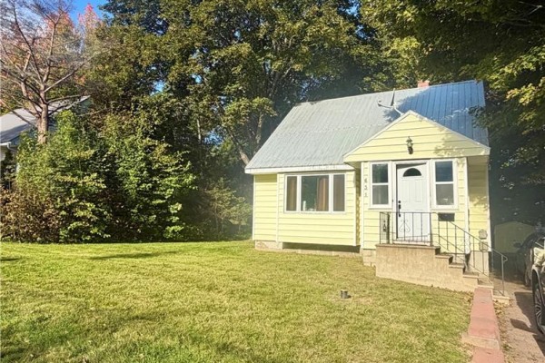 Side angle of a yellow house with a large wooden deck and surrounding trees. - 631 Mitchell Street, Fredericton