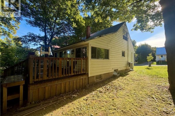 Rear view of the yellow house showing the wooden deck and surrounding lawn. - 631 Mitchell Street, Fredericton