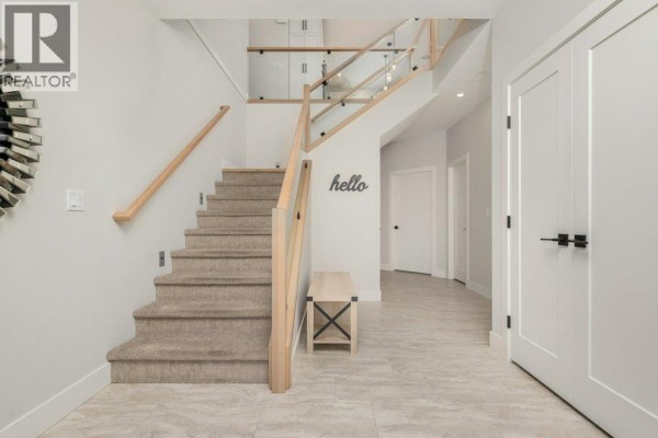 Open-concept living room and kitchen with a large sectional sofa, coffee table, island seating, and dining area. - 631 Mt Ida Crescent, Coldstream