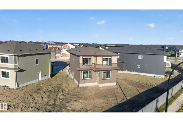 Construction site view of a beige townhouse with surrounding dirt and fence. - 6320 24 St Ne Ne, Rural Leduc County