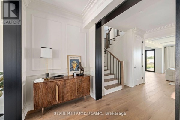 Foyer with a wooden console table, staircase, and view towards the backyard. - 6326 Old Garrison Boulevard, London South