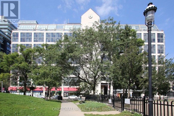 View of building from across a park with trees and a black metal fence. - 633 - 222 The Esplanade, Toronto