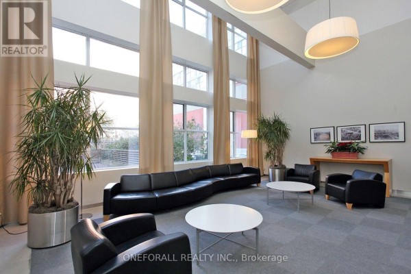 Lobby seating area with black leather couches, white tables, and large windows. - 633 - 222 The Esplanade, Toronto