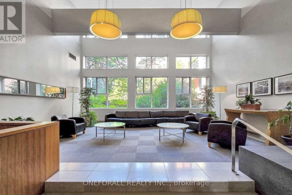 Lobby lounge with curved black sofa, coffee tables, and modern pendant lights. - 633 - 222 The Esplanade, Toronto