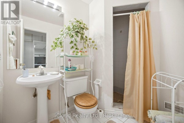 Bathroom with pedestal sink, wooden toilet seat, and shower with tan curtain - 6332 Glen Meadows Road Mississauga