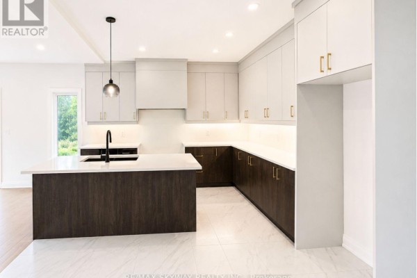 Modern kitchen with two-tone grey and white cabinets, a dark wood island, and white countertops. - 6333 Jewel Common, Niagara Falls