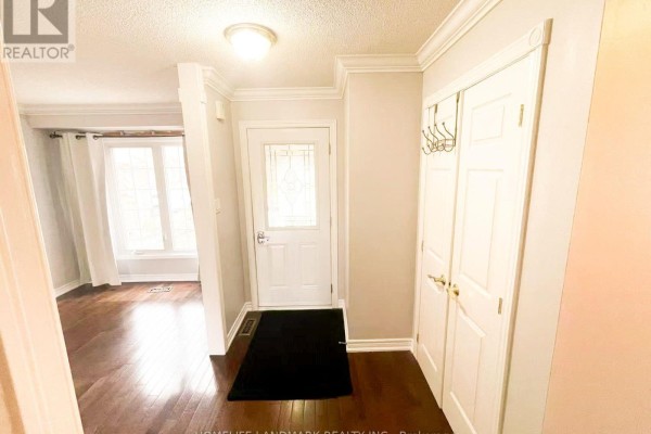 Interior entryway with a white front door, hardwood floors, and a closet. - 6337 Martel Court, Mississauga