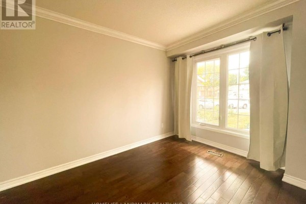 Living room with large bay windows, beige walls, and dark hardwood floors. - 6337 Martel Court, Mississauga
