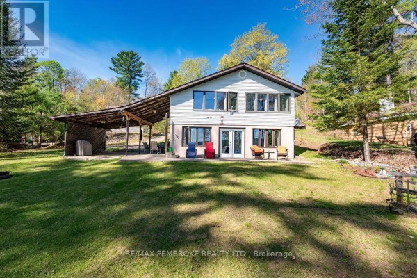 Side exterior of a house with a large covered carport, grassy lawn, and trees. - 634 Goldfinch Way, Head, Clara And Maria