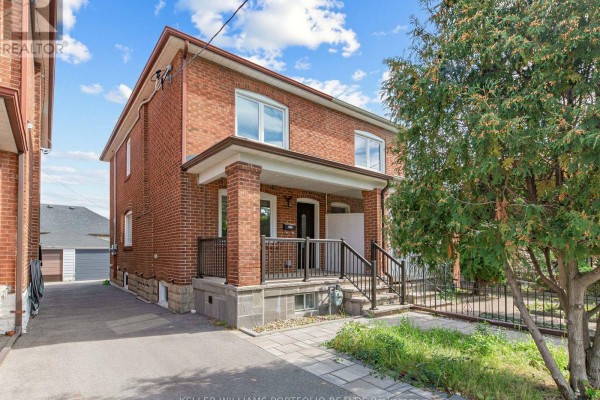 Front exterior of a red brick house with a covered porch, dark railings, and a paved driveway. - 635 Glenholme Avenue, Toronto