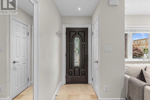 Interior hallway showing a dark front door with a decorative glass insert and cream-colored walls. - 635 Glenholme Avenue, Toronto