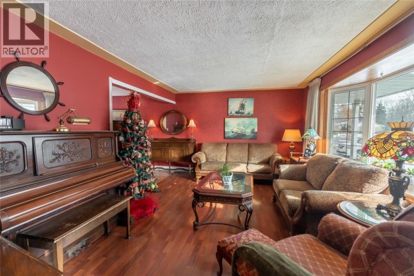Living room featuring red walls, wooden flooring, and a piano - 635 Highbury Park, Sarnia