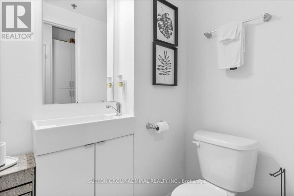 Compact bathroom featuring a modern sink, toilet, and framed wall art - 636 - 1900 Simcoe Street N, Oshawa