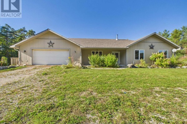 Front exterior of a beige house with a double garage and green lawn. - 636 Kairshea Avenue, Huron Kinloss