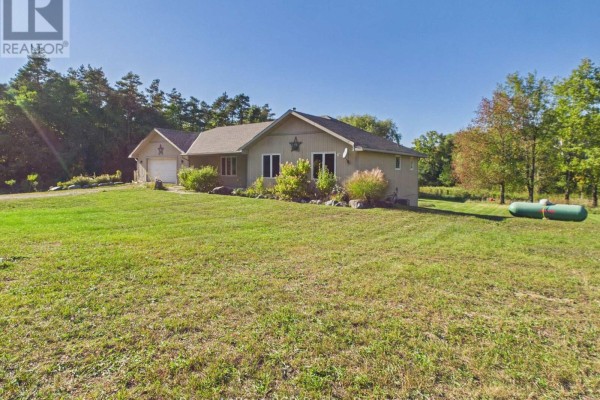 Side exterior view of a beige house with a garage and surrounding grass. - 636 Kairshea Avenue, Huron Kinloss
