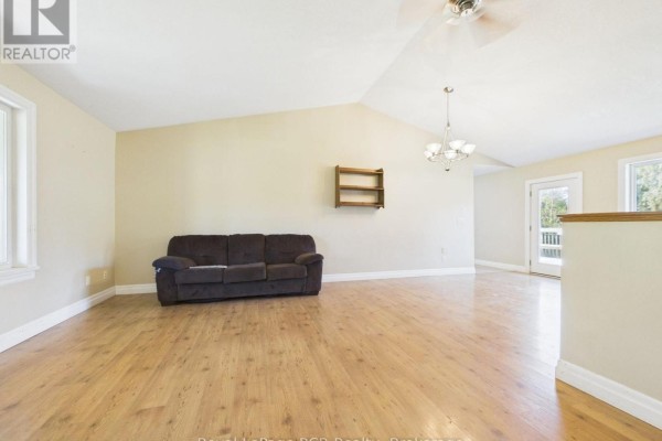 Living room with a brown sofa, hardwood floors, and vaulted ceiling. - 636 Kairshea Avenue, Huron Kinloss