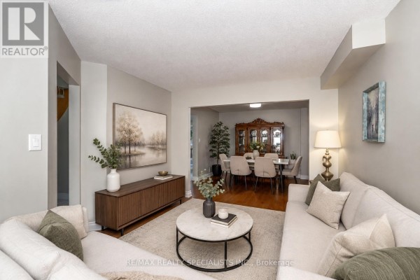 Living room with light grey walls, a sectional sofa, coffee table, and adjacent dining room. - 6369 Longspur Road, Mississauga