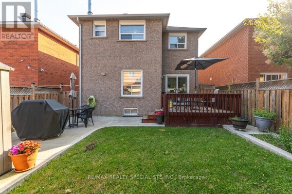 Backyard with a wooden deck, lawn, patio area, grill, and wooden fence. - 6369 Longspur Road, Mississauga