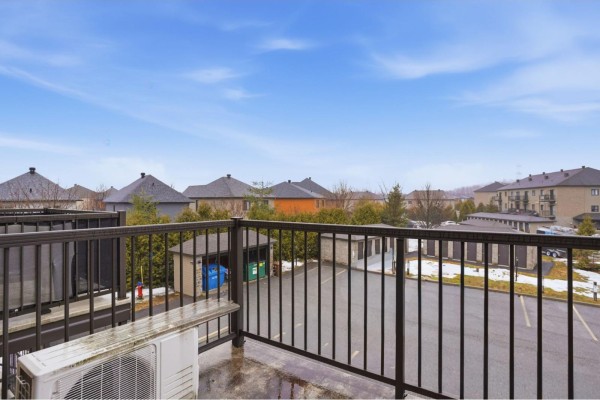 View from a balcony overlooking a parking lot with residential buildings and trees in the background. - 637 Boul. Des Grives, #3, Gatineau