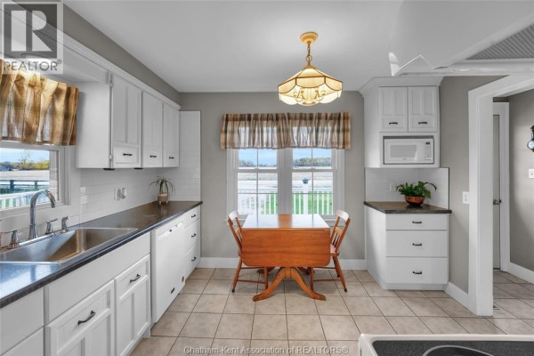 Kitchen featuring white appliances, tile flooring, and access to living area. - 637 Wilkesport Line, Sombra