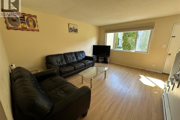 Living room with a window overlooking trees, black leather sofas, and a television on a stand. - 6370 Park Drive Unit# 11, Oliver