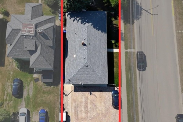 Aerial view of a rectangular fourplex building with a grey roof, adjacent driveway, and surrounding properties. - 638 7th Street, Humboldt
