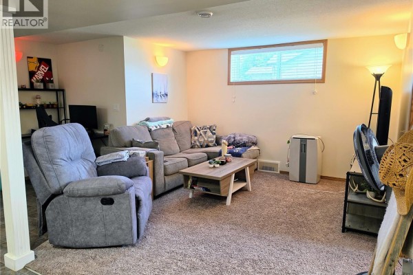 Living room with a grey sectional sofa, recliner, coffee table, television, and carpeted floor. - 638 7th Street, Humboldt