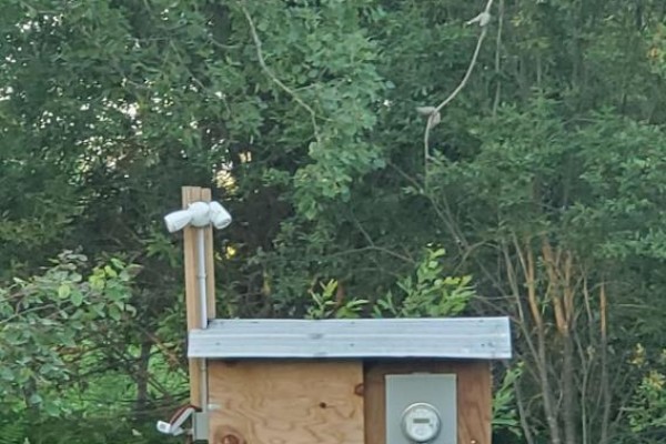 Outdoor electrical box with meter, connected to wooden post and overhead wiring in wooded area. - 638 Chenier Road, Papineau Cameron