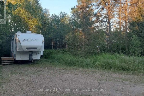 Fifth-wheel trailer parked on a gravel surface beside a grassy area and surrounded by trees. - 638 Chenier Road, Papineau Cameron