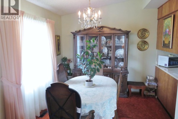 Dining room with a table, hutch filled with china, and a crystal chandelier. - 639 Acadia Drive, Saskatoon