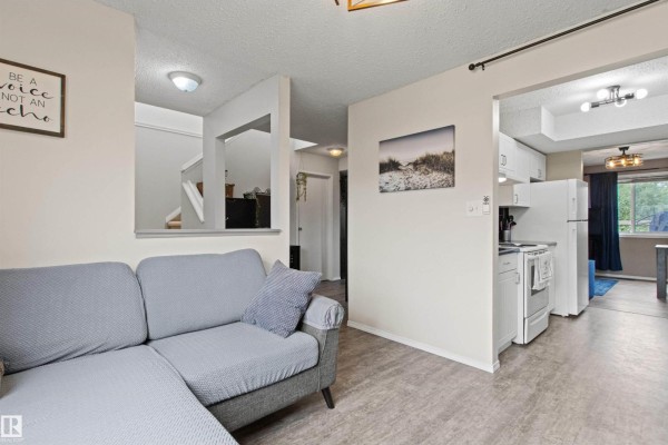 Front view of light grey townhouses with attached garages and parking lot. - #64 3221 119 St Nw, Edmonton