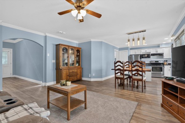 Open-concept living and dining area leading to a white kitchen with stainless steel appliances. - 64 6449 Blackwood Lane, Sardis South, Chilliwack