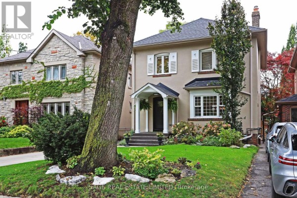 View of the house from the side yard, with a large tree in the foreground. - 64 Cheritan Avenue, Toronto