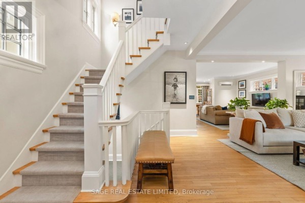 Interior view of the foyer with a white staircase and a living room in the background. - 64 Cheritan Avenue, Toronto