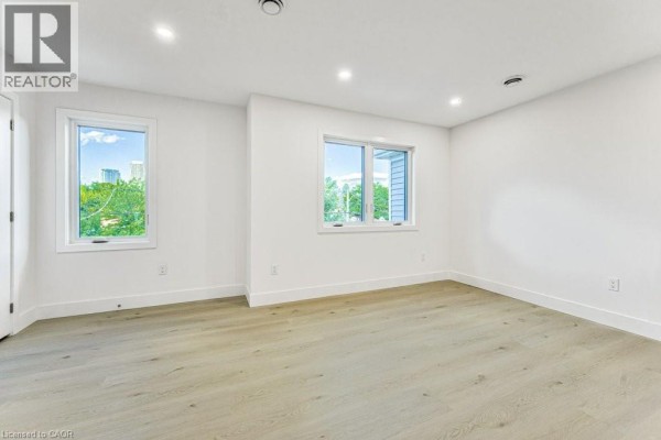 Kitchen with white cabinets, island with sink, and hallway leading to rooms on the left. - 64 Gage Avenue Unit# 2, Kitchener