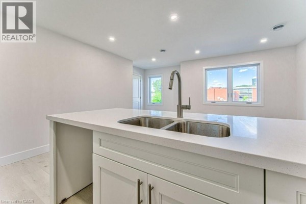 U-shaped kitchen with white cabinets, countertop, sink, and island. - 64 Gage Avenue Unit# 2, Kitchener