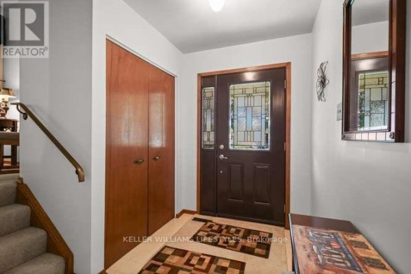 Interior entryway with a dark brown door with glass panels, wooden closet doors, and patterned rugs. - 64 Haliburton Crescent, London South