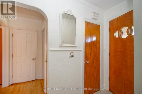 Interior hallway with two wooden doors, a mirror, and an arched doorway. - 64 Harris Avenue, Oshawa