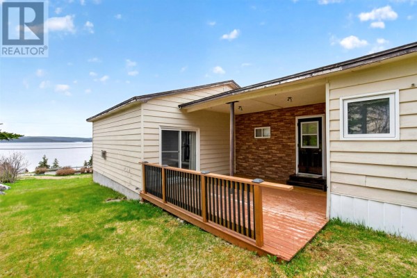 Wooden deck and exterior wall of a house with a sliding door and a brick accent. - 64 Main Road, Broad Cove  Dildo