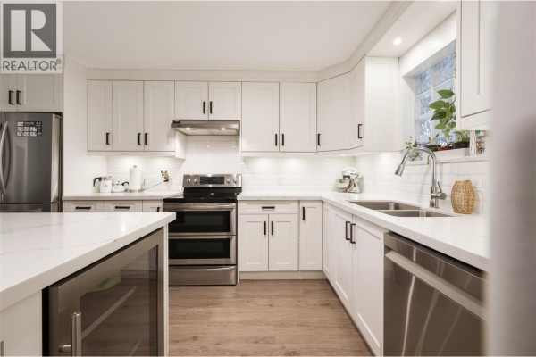 Kitchen with white cabinets, stainless steel appliances, quartz countertops, and a double sink. - 640 Main Street Unit# 108, Okanagan Falls
