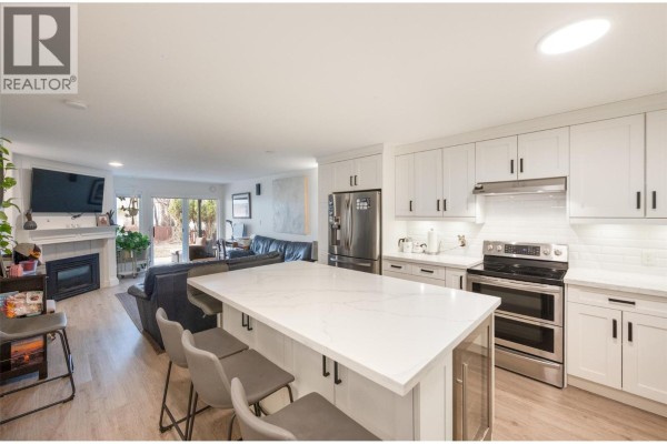 Open concept living space with a kitchen island, living room with fireplace, and patio doors. - 640 Main Street Unit# 108, Okanagan Falls