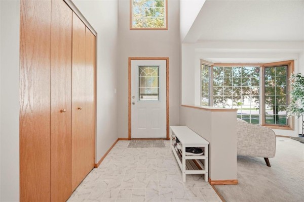 Entrance hallway with a high ceiling, wood grain closet doors, and a bay window. - 640 Scurfield Boulevard, Winnipeg