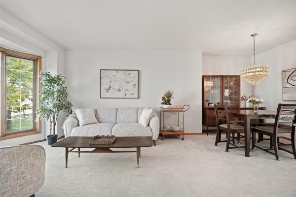Living and dining room area with a grey sofa, wood dining set, and crystal chandelier. - 640 Scurfield Boulevard, Winnipeg