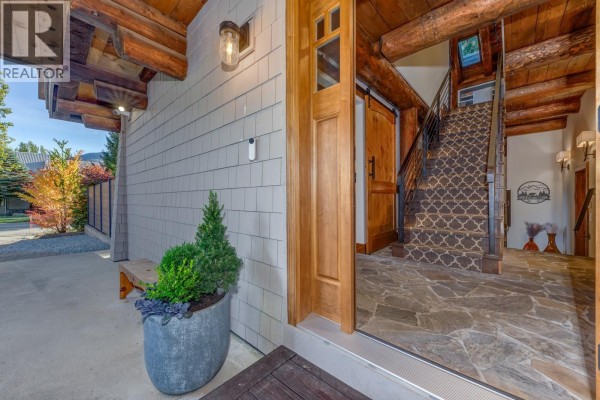 Entranceway with a stone floor, wooden door, and staircase with patterned carpet. - 6403 St Andrew's Way, Whistler