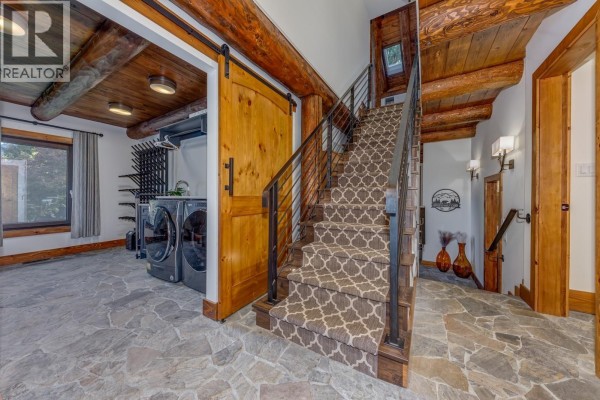 Laundry room with washer and dryer adjacent to a staircase with stone flooring. - 6403 St Andrew's Way, Whistler